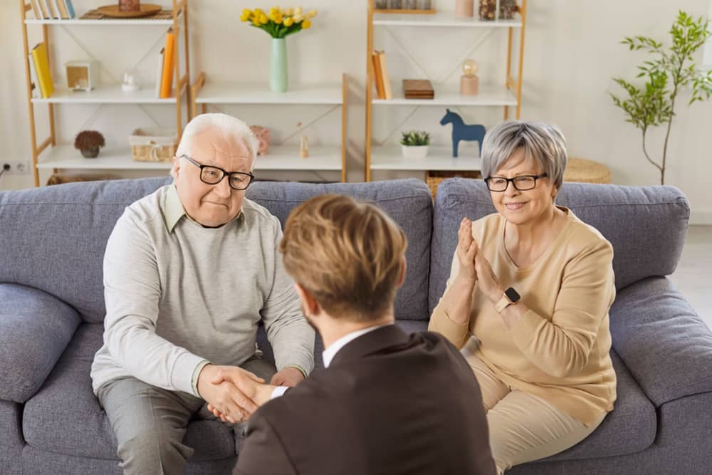 Couple shaking hands with a real estate agent while discussing a home reservation agreement