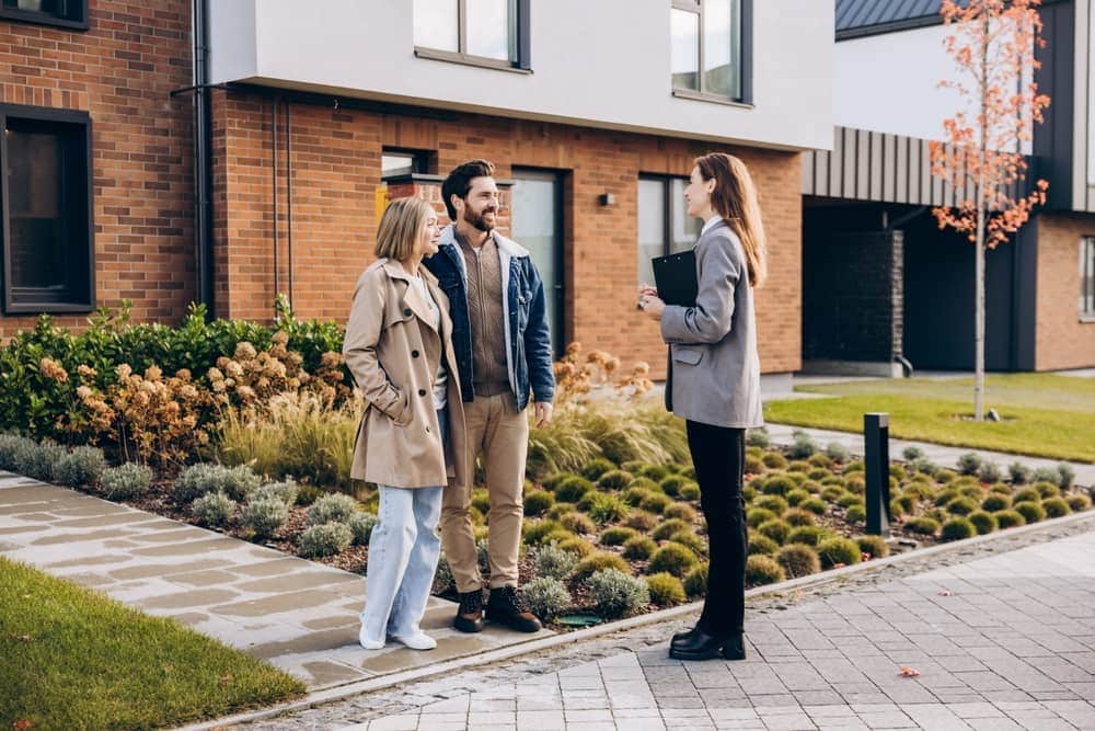 Real estate agent showing a new home exterior to a couple comparing homes for sale in the Bullard, TX area